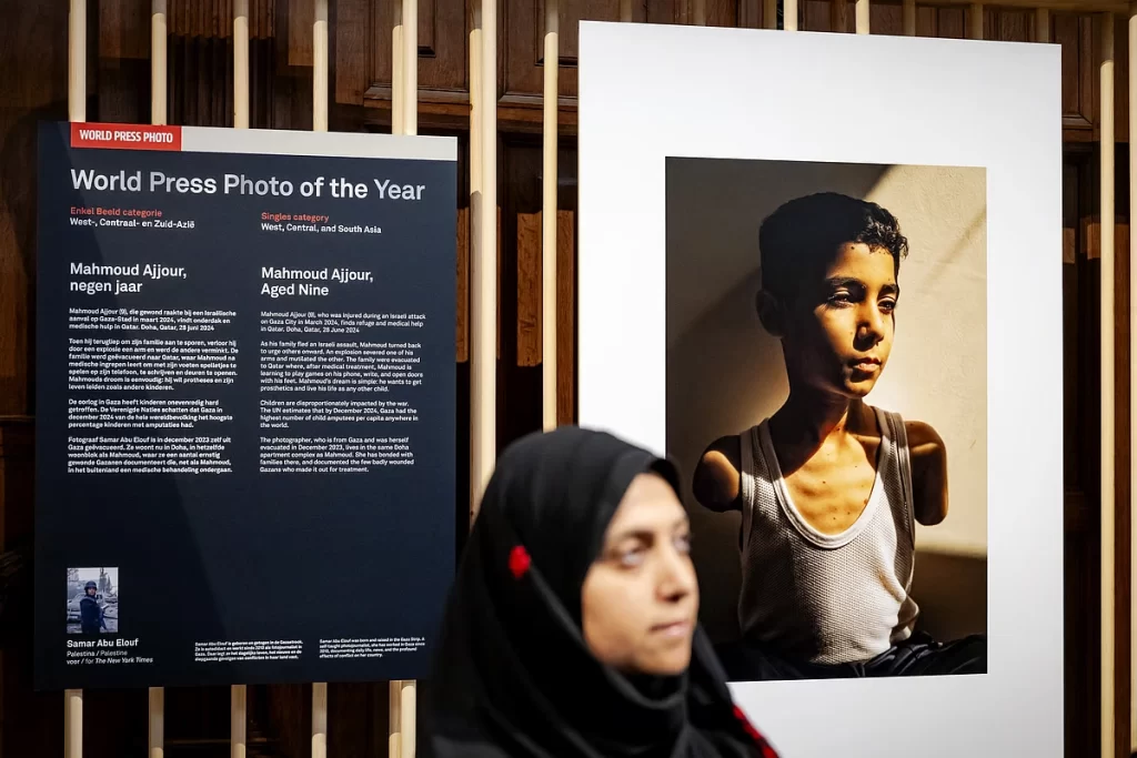 Elouf standing infront of her prize winning picture of amputee Gazan boy